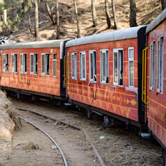 Obraz premium Toy Train moving on mountain slopes, beautiful view, one side mountain, one side valley moving on railway to the hill, among green natural forest. Toy train from Kalka to Shimla in India, Indian Train