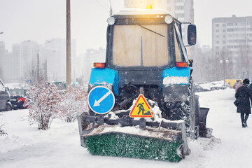 Snow removal tractor clear snowy walkway at city street with plough and sweeping brush. Tractor...