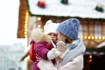 Obraz premium Mother and daughter are walking around the city on Christmas and New Year holidays. Parent and little child having fun outdoors