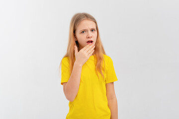 Portrait of teen girl looking shocked and concerned at camera, open mouth and furrow eyebrows startled, hear awful terrible news, stands in casual yellow t shirt over white studio background