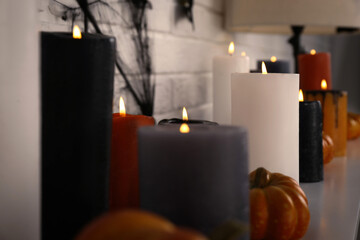 Burning candles and different Halloween decor indoors