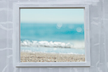 Views of sandy beaches through window frames and raw cement walls.