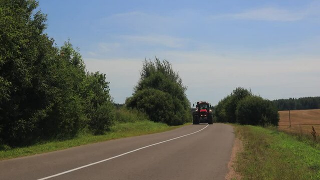 Agricultural machinery rides on the road in the field on a summer day