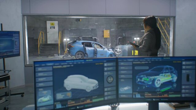 Female and male engineers in experimental crash test laboratory watching process of traffic accident simulation, to get safety parameters of a new electro eco-friendly car body using computer system.