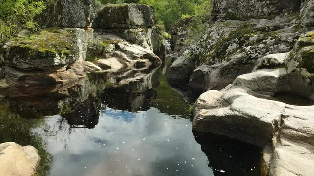 Vuelo de dron hacia delante cerca del agua en rio relajante con bonitos reflejos en el agua en Galicia