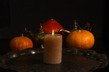 Yellow-orange pumpkins candle tray Aladdins lamp on a black background the concept of Halloween and the autumn harvest of pumpkin close-up copyspace from above