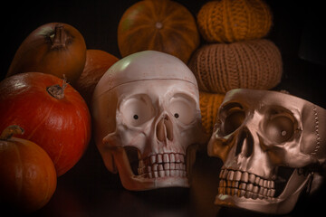 Yellow-orange pumpkins with candles and skulls on a black background the concept of Halloween and the autumn harvest of pumpkin close-up copyspace from above