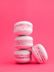 tower of pink pastel macarons close-up on bright viva magenta trend 2023 color background, Stack of four strawberry or raspberry cookies. Vertical.