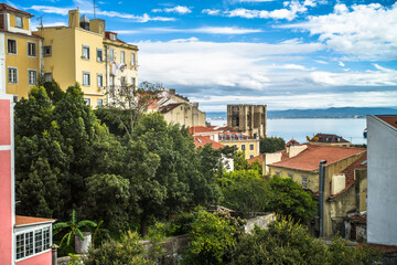 Fototapeta na wymiar historic buildings of the old town of lisbon. Old colorful buildings, narrow streets, historic churches. Tiled roofs. View from the top of the viewpoint on the tenement houses and monuments. Clouds