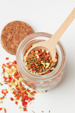 Top view of mixed pieces of dried vegetables  in wooden spoon  and glass jar on white background