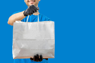 Delivery man with paper bag. Courier in uniform t-shirt, gloves service fast delivering orders....