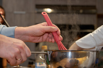 Cooking process: whisking sauce in a saucepan with rising steam
