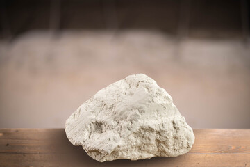 A large piece of edible mountain chalk lies on a wooden board on a blurred background