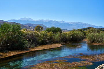Bushes and reeds along the river and view of Lefka Ori mountain in Georgioupoli village on Crete island