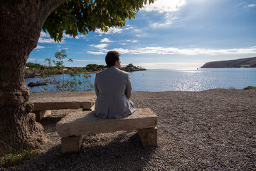 Viajero solitario meditando sobre el frío banco de piedra bajo el verde árbol que le ofrece...