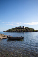 Fototapeta na wymiar Lancha motora atada a las rocas sobre el mar del pueblo de Cadaqués con una pequeña isla de fondo con mucha naturaleza.