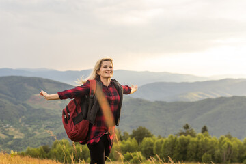 Beautiful woman sitting on mountain top and contemplating landscape.