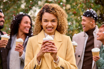 Group Of Friends Wearing Coats Standing Outside In Snow Holding Takeaway Hot Chocolate Drinks