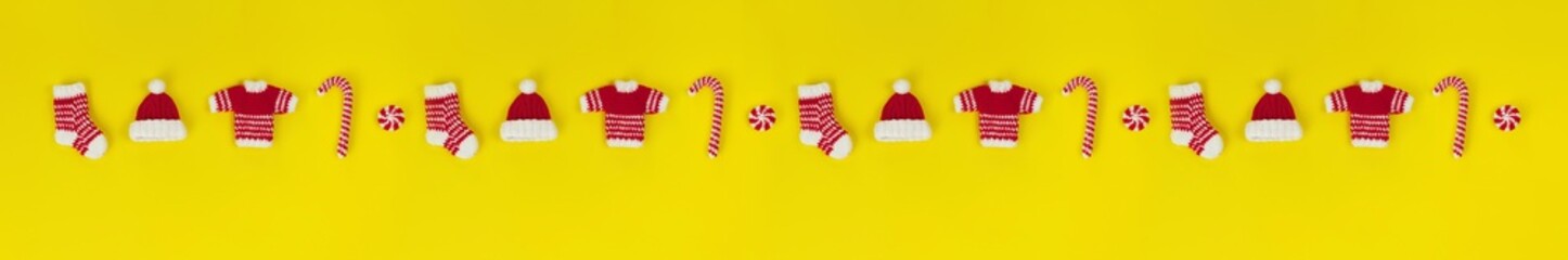 Fototapeta na wymiar banner decorative knitted ornaments sock, sweater, hat and caramel in red and white color in row on yellow background