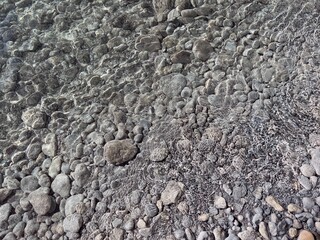 Pebbles stones sand in clear water background.