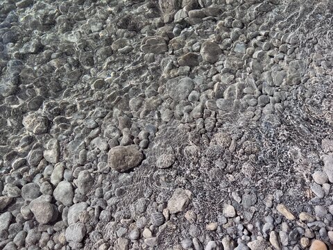 Pebbles stones sand in clear water background.