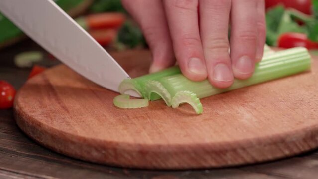 person cutting leeks on a wooden board.
