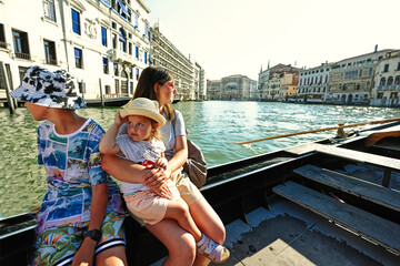 Mother with kids sit at gondola in Venice,  Italy.