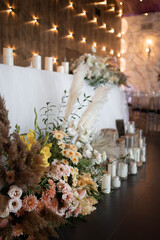 Romantic boho main table. Wedding decor with dried flowers floristry, stumps, and candles, boho style. Pampas grass