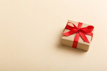 Wrapped christmas or other holiday handmade present in craft paper with colored ribbon. Present box, decoration of gift on table, top view with copy space