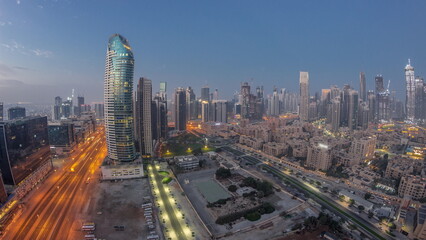 Naklejka na ściany i meble Dubai's business bay towers aerial night to day timelapse. Rooftop view of some skyscrapers