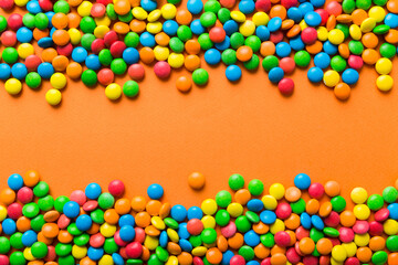 Obraz premium Mixed collection of colorful candy, on colored background. Flat lay, top view. frame of colorful chocolate coated candy
