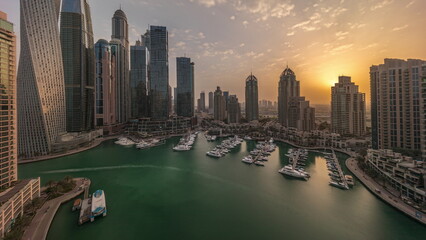 Obraz premium Sunrise over Dubai marina tallest skyscrapers and yachts in harbor aerial morning timelapse.