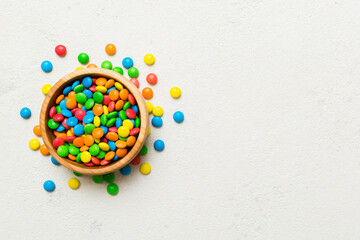 Multicolored candies in a bowl on a colored background. birthday and holiday concept. Top view with copy space