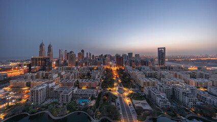 Panorama of skyscrapers in Barsha Heights district and low rise buildings in Greens district aerial night to day timelapse.