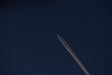 The plane leaves a trail on the blue sky