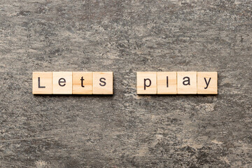 lets play word written on wood block. lets play text on cement table for your desing, concept