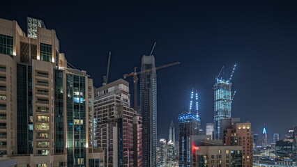 Panorama showing aerial cityscape night timelapse with illuminated architecture of Dubai downtown.