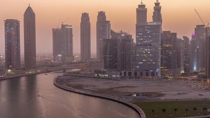 Cityscape of skyscrapers in Dubai Business Bay with water canal aerial day to night timelapse