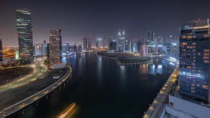 Fototapeta na wymiar Panorama showing cityscape of skyscrapers in Dubai Business Bay with water canal aerial night timelapse
