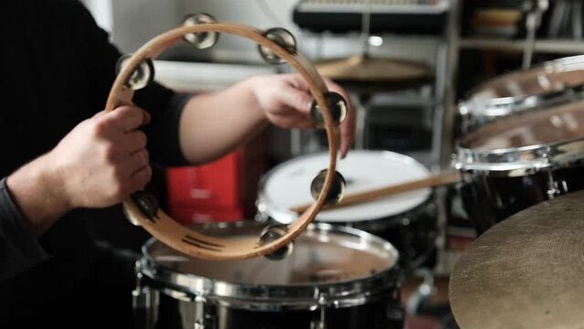 Man hands with tambourine in music recording studio. Guy playing on traditional folk musical instrument