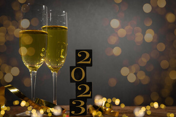 New Year New Year's Eve Sylvester celebration holiday greeting card background - Cubes with year 2023 and sparkling wine or champagne glasses on wooden table.