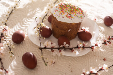 Easter cake and painted eggs. Blooming bouquet laying on the table near.