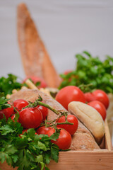 Fresh bio ripe red tomatoes with white bread, parsley leaves in a wooden box in a street food market, close up, vertical