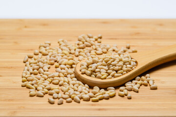 Pine nuts are scattered on a wooden table close-up.