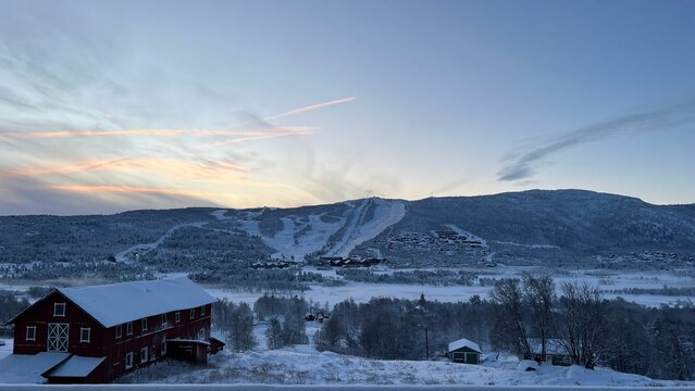 Beautiful landscape of a town covered in snow at sunset with a cloudy sky in the background, Norway