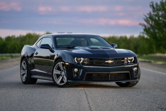 Shiny luxury Chevrolet Camaro on a country road at sunset