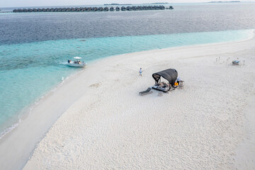 Aerial view: lonely sandbank in the Maldives with a table and sun loungers for romantic dinners, North Male Atoll, Maldives , Asia