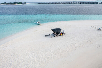 Aerial view: lonely sandbank in the Maldives with a table and sun loungers for romantic dinners, North Male Atoll, Maldives , Asia