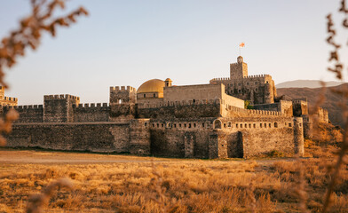 View of the medieval Akhaltsikhe Castle in southern Georgia at sunset. It's a hot summer day with...