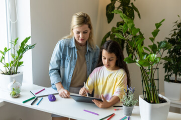 Obraz premium Mother and daughter reading E-book together at home